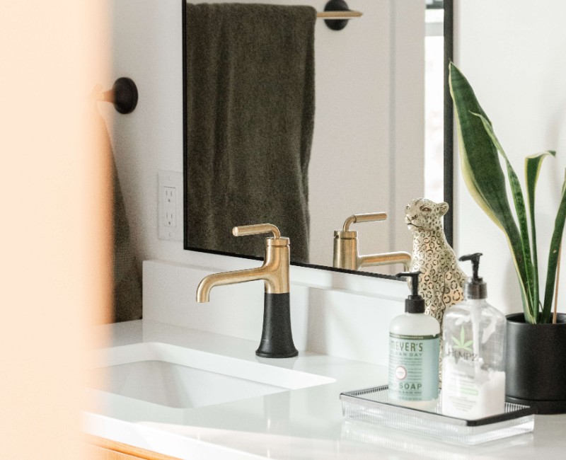 A bold black-and-white ensuite bath with frameless glass, warm wood cabinetry, and a custom sliding door — part of a NARI award-winning attic conversion by Chads Design Build in Madison, WI.