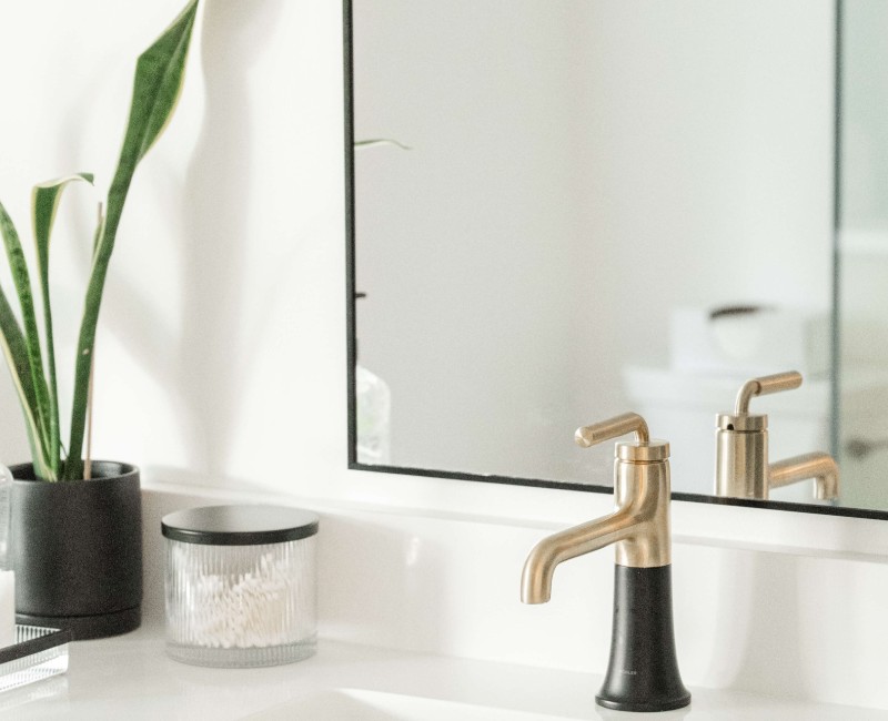 A bold black-and-white ensuite bath with frameless glass, warm wood cabinetry, and a custom sliding door — part of a NARI award-winning attic conversion by Chads Design Build in Madison, WI.