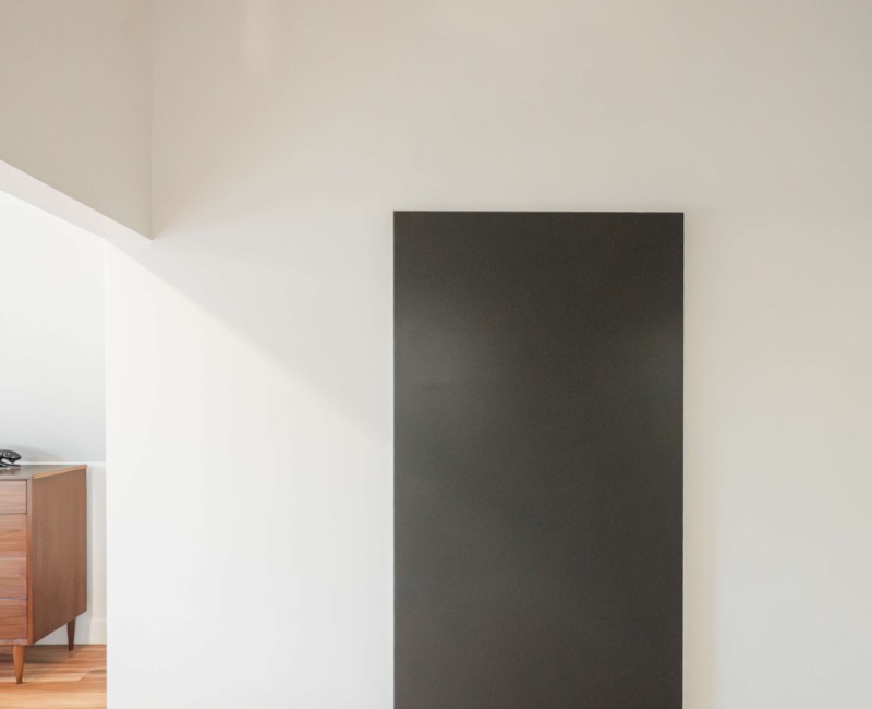 A bold black-and-white ensuite bath with frameless glass, warm wood cabinetry, and a custom sliding door — part of a NARI award-winning attic conversion by Chads Design Build in Madison, WI.