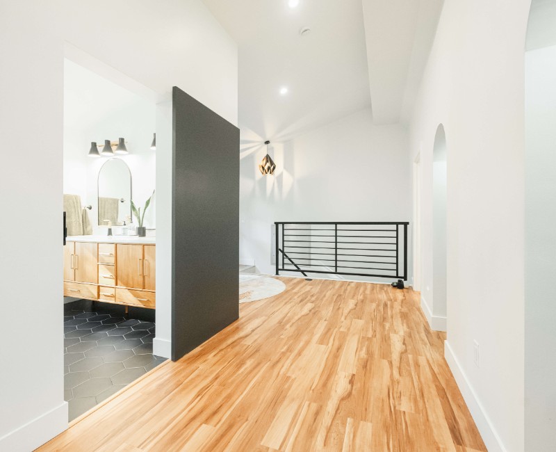 A bold black-and-white ensuite bath with frameless glass, warm wood cabinetry, and a custom sliding door — part of a NARI award-winning attic conversion by Chads Design Build in Madison, WI.