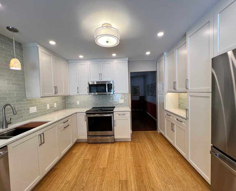We remodeled this kitchen in Madison, WI to be bright and functional. Our team adjusted the layout, installed bamboo flooring, and added a peninsula. We installed white linen cabinets, white marble countertops, and a blue/gray tile backsplash to finish the look.