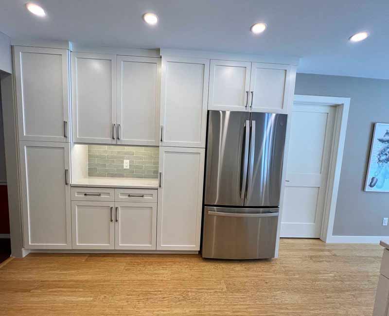 We remodeled this kitchen in Madison, WI to be bright and functional. Our team adjusted the layout, installed bamboo flooring, and added a peninsula. We installed white linen cabinets, white marble countertops, and a blue/gray tile backsplash to finish the look.