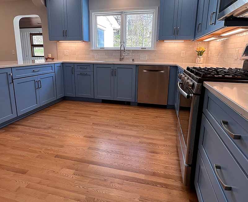 This kitchen in Madison, WI was remodeled to provide ample space for the family to gather and cook together. It features blue cabinetry and white and gray subway tiles.