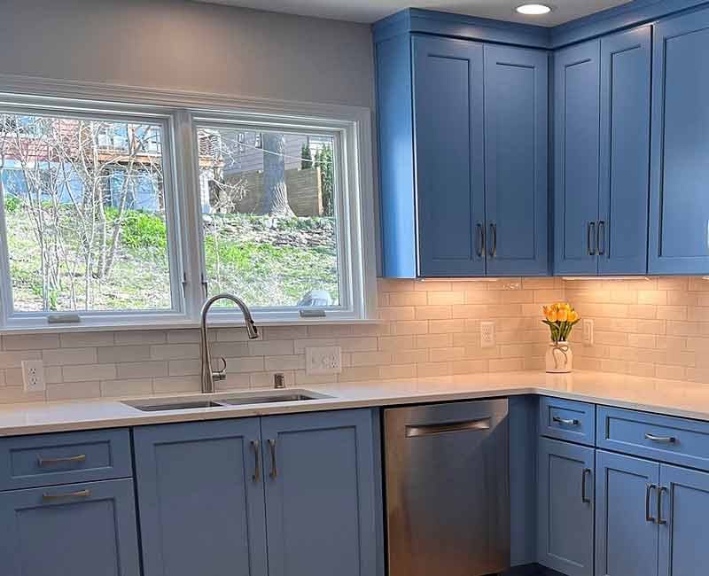 This kitchen in Madison, WI was remodeled to provide ample space for the family to gather and cook together. It features blue cabinetry and white and gray subway tiles.