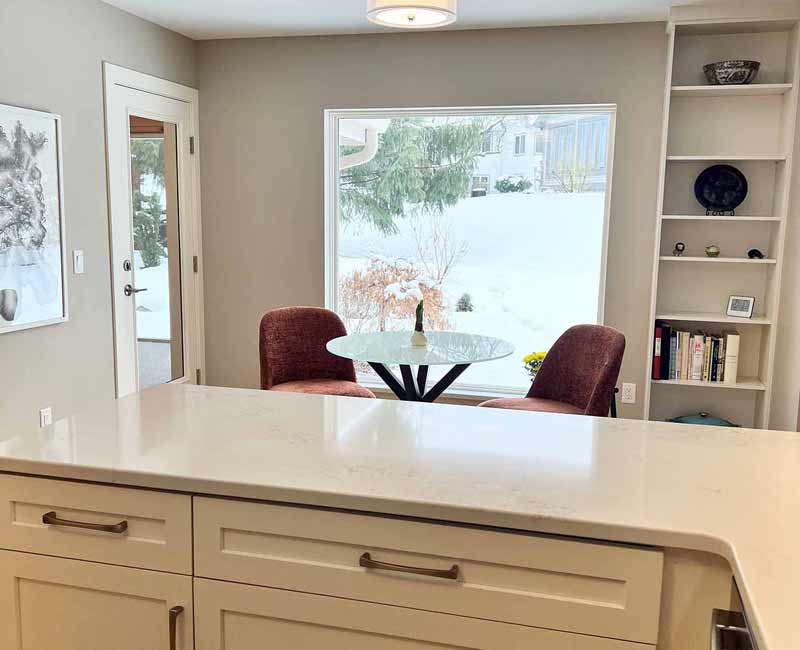 We remodeled this kitchen in Madison, WI to be bright and functional. Our team adjusted the layout, installed bamboo flooring, and added a peninsula. We installed white linen cabinets, white marble countertops, and a blue/gray tile backsplash to finish the look.